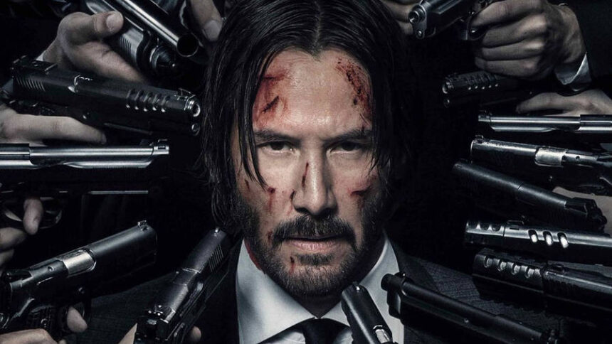 Keanu Reeves in John Wick Chapter 4 standing under neon lights with gun drawn